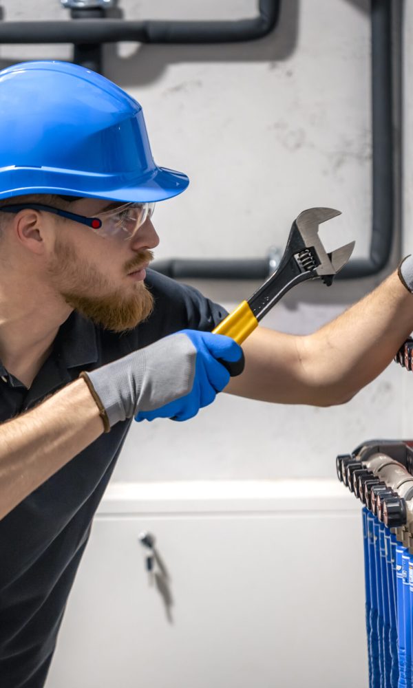 The technician checking the heating system in the boiler room. Adjusting heating valves in a residential building. A plumbing and heating technician works.